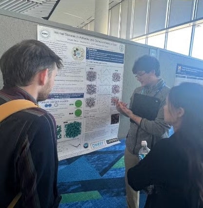 Logan presenting his poster to two other students.